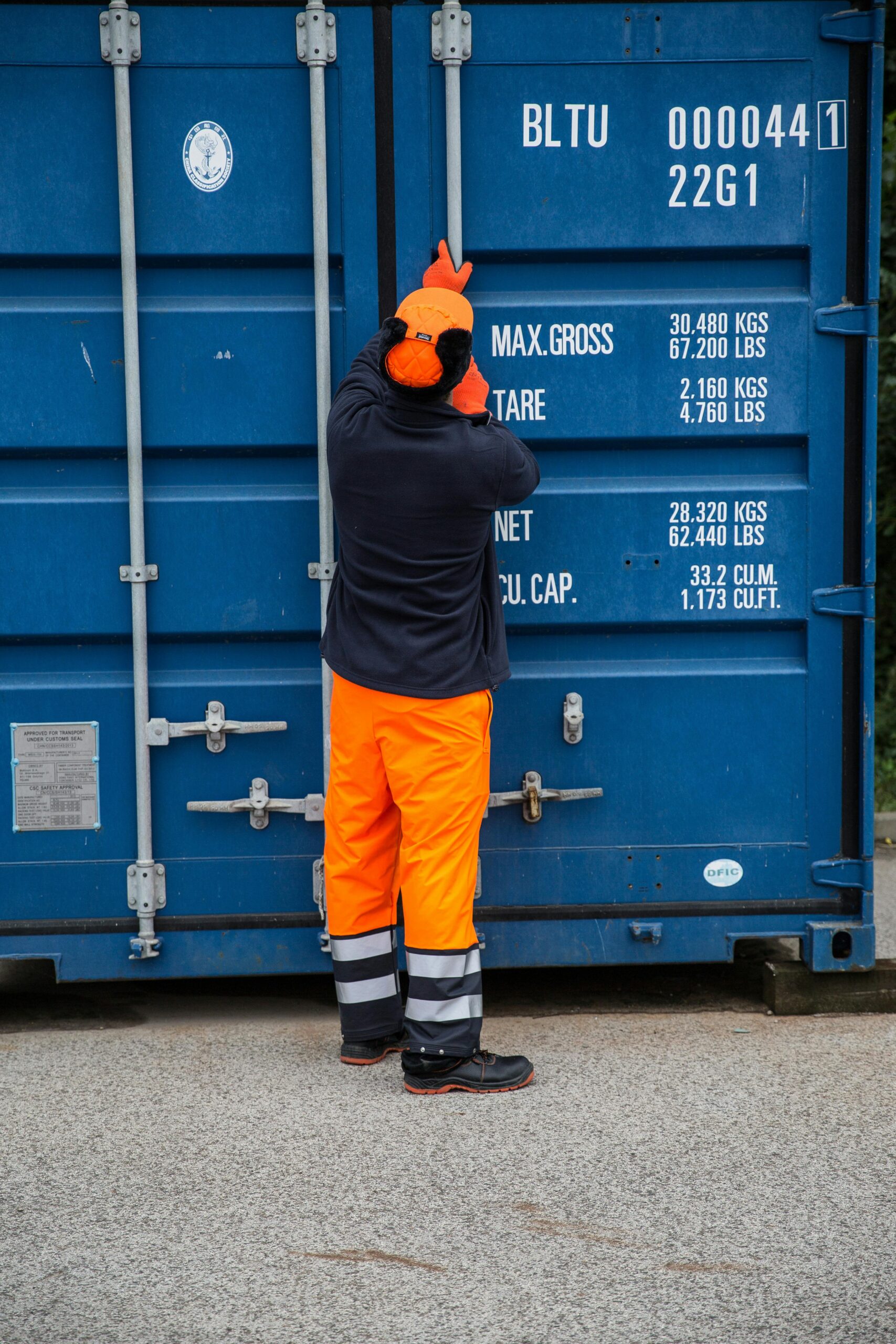 Industrial worker securing a shipping container outdoors, highlighting safety and logistics.